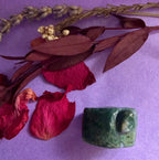 Moss Agate crystal house carving back view on purple background with red rose petals — The Crooked Moon
