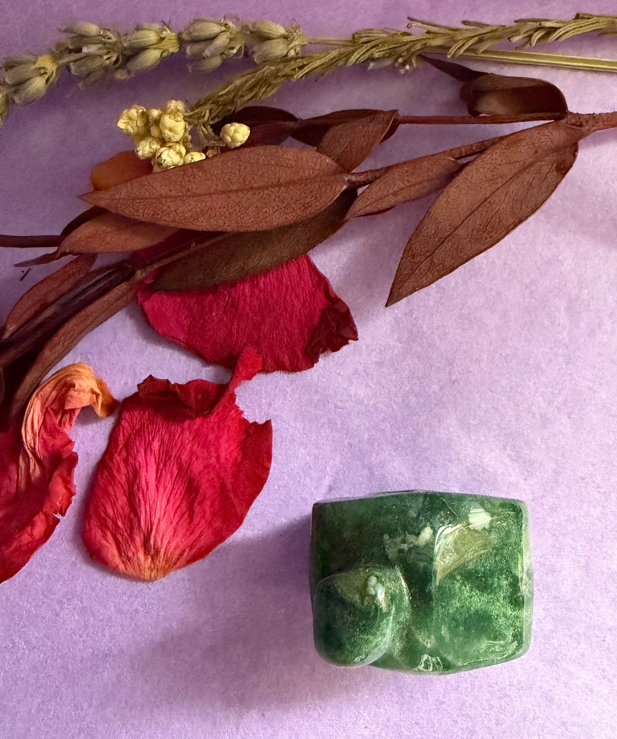 Moss Agate crystal house carving back view on purple background with red rose petals — The Crooked Moon