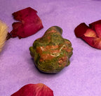 Unakite crystal frog carving back view on purple background with rose petals — The Crooked Moon