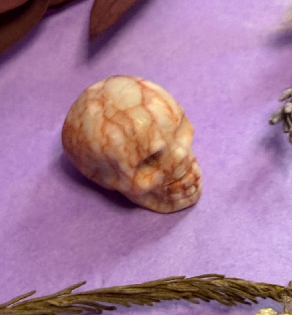 Crystal skull carving close-up on purple background — The Crooked Moon