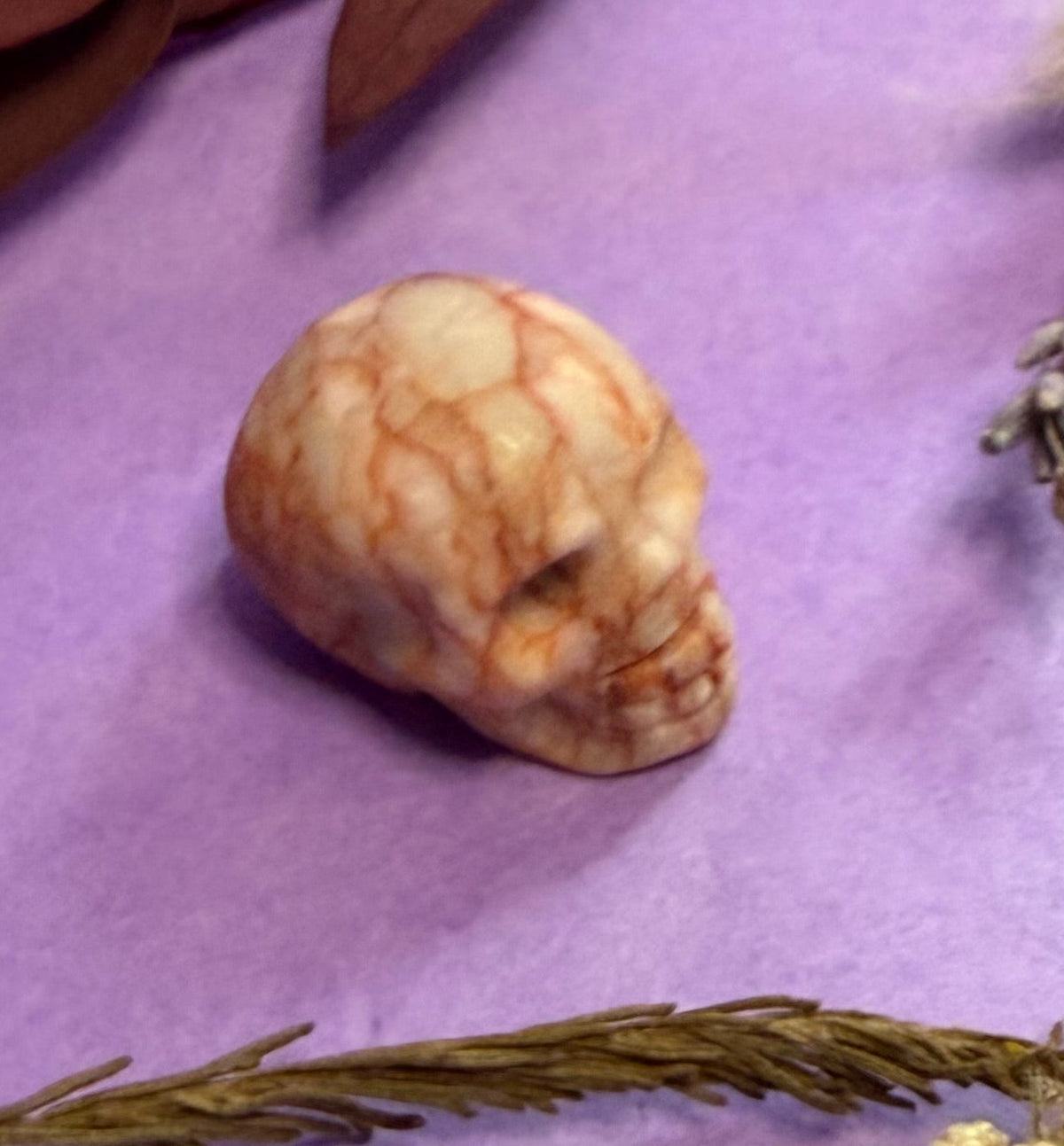 Crystal skull carving close-up on purple background — The Crooked Moon
