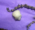 New Jade crystal skull carving on purple background with dried lavender — The Crooked Moon