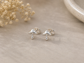 Mushroom Stud Earrings Sterling Silver — pair of small polished silver mushroom stud earrings with engraved cap detail on grey stone surface with dried gypsophila"