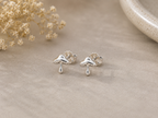 Mushroom Stud Earrings Sterling Silver — pair of small polished silver mushroom stud earrings with engraved cap detail on grey stone surface with dried gypsophila"