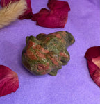 Unakite crystal frog carving side view on purple background with rose petals — The Crooked Moon