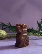 Red Goldstone crystal dog carving side view on lilac background with dried botanicals — The Crooked Moon