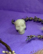 New Jade crystal skull carving side view on purple background — The Crooked Moon