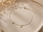 "Dual Star CZ Bracelet Sterling Silver product shot — delicate silver cable chain bracelet with two pavé cubic zirconia star charms of different sizes, spring ring clasp and extender chain, on cream ceramic dish with dried gypsophila"