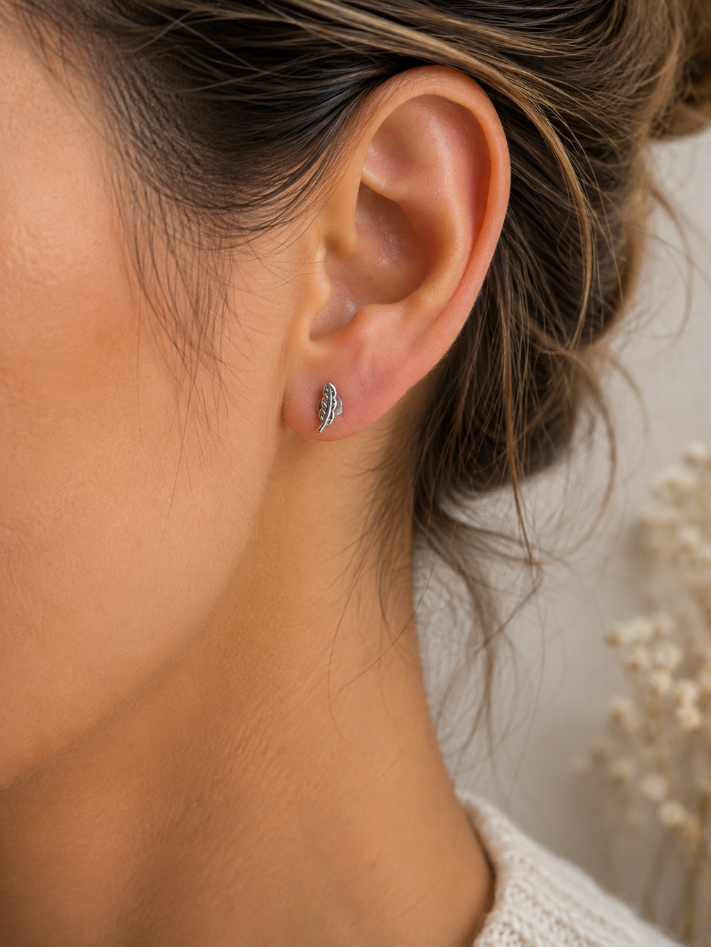 Feather Stud Earrings Sterling Silver worn shot — single silver feather stud earring shown worn on model's ear lobe, displaying size and fit"