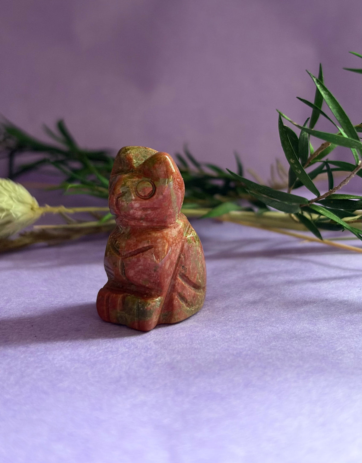 Unakite crystal cat carving side view on lilac background with dried botanicals — The Crooked Moon