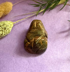 Tiger's Eye crystal frog carving top view on lilac background with dried pampas grass — The Crooked Moon