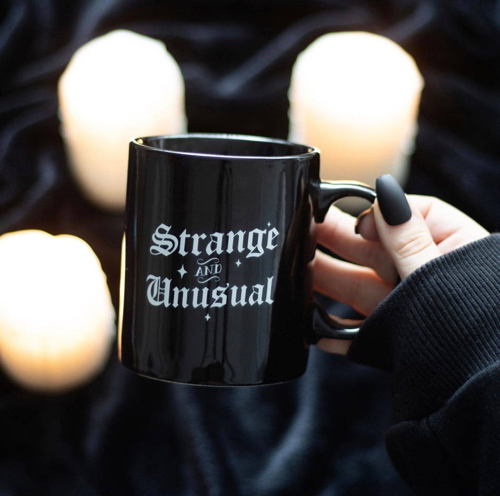 Strange and Unusual Mug lifestyle shot held with candles in background