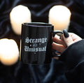 Strange and Unusual Mug lifestyle shot held with candles in background