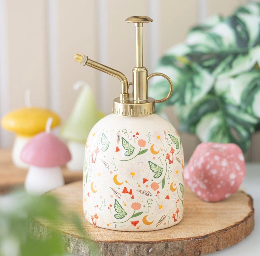 Fairy Folk Print Ceramic Plant Mister lifestyle shot on wooden slice with mushroom candles and plants