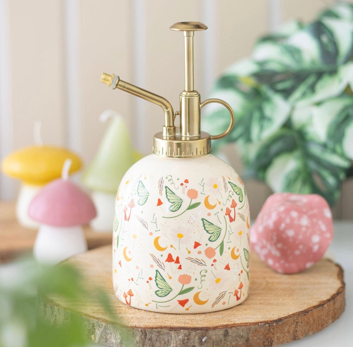 Fairy Folk Print Ceramic Plant Mister lifestyle shot on wooden slice with mushroom candles and plants