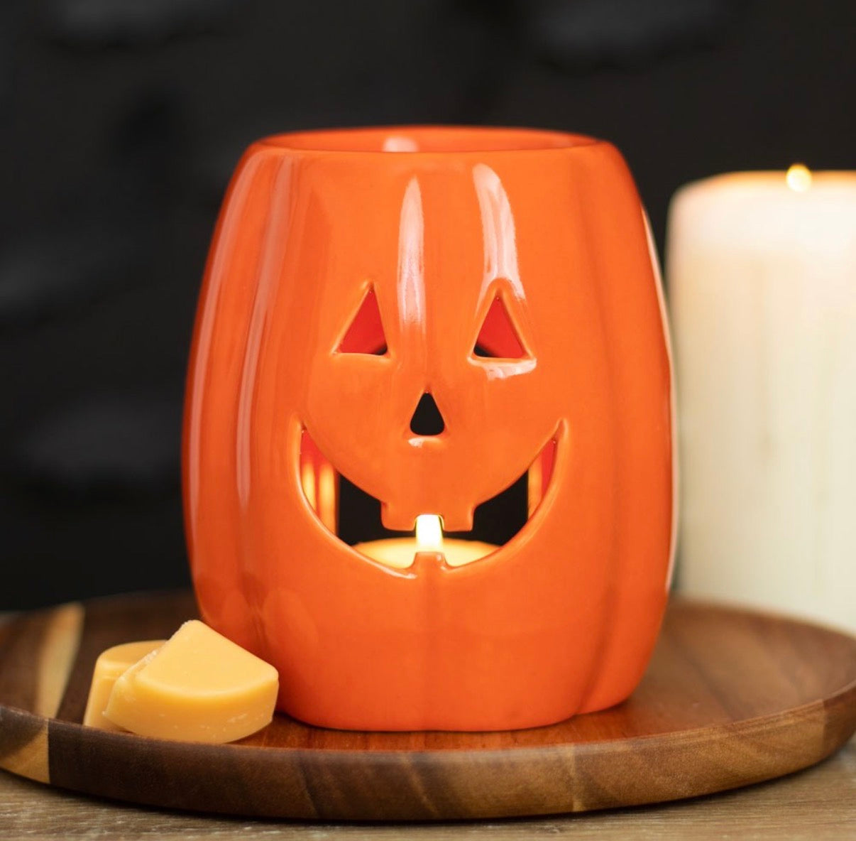 Jack-o'-Lantern Pumpkin Wax Melt Burner - lifestyle shot lit with wax melts on wooden board