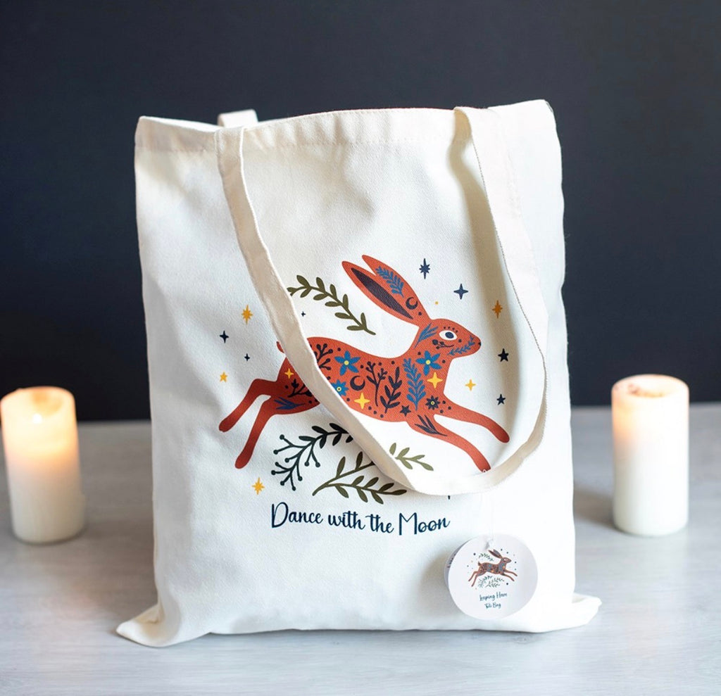 Dance with the Moon Jumping Hare Tote Bag lifestyle shot with candles and button badge