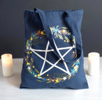 Solstice Wreath Tote Bag lifestyle shot with candles showing pentagram wreath print