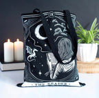 The Reader Tarot Tote Bag lifestyle shot with candles and plant