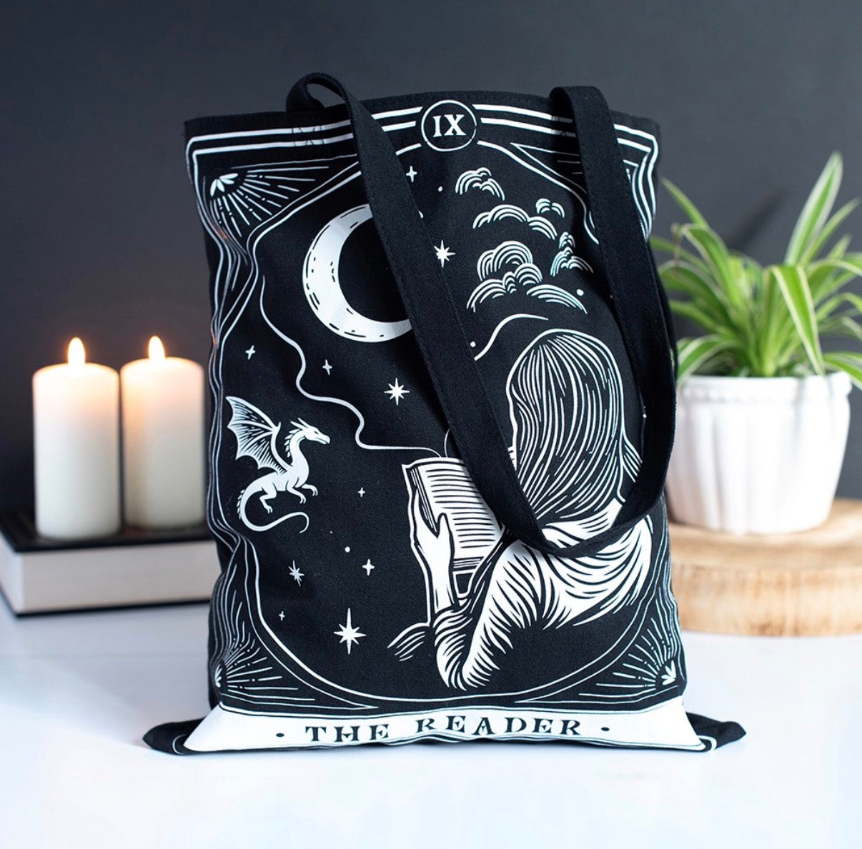 The Reader Tarot Tote Bag lifestyle shot with candles and plant