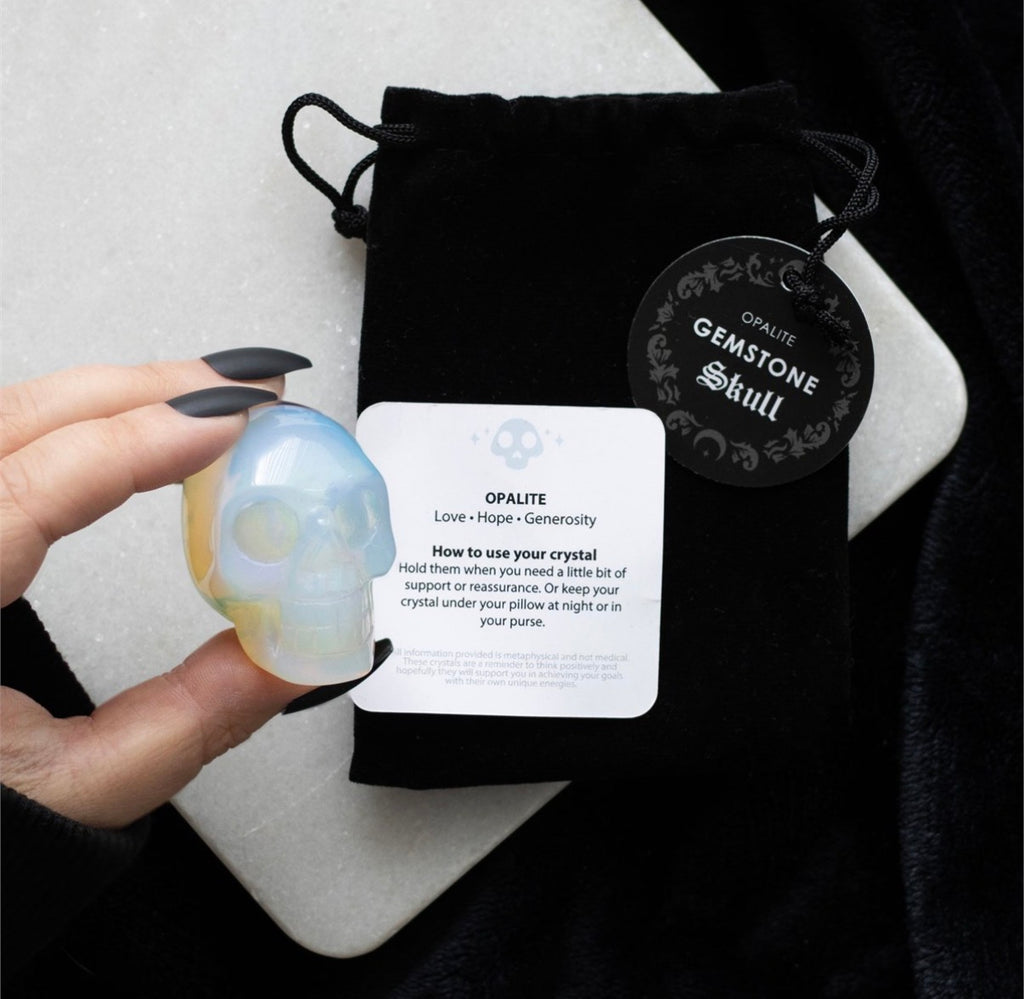 Opalite Gemstone Skull held in hand styled shot with velvet pouch