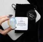 Opalite Gemstone Skull held in hand styled shot with velvet pouch
