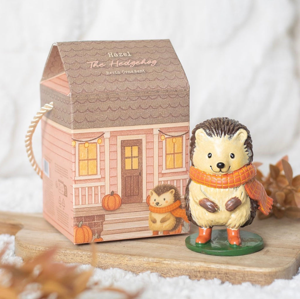 Hazel The Hedgehog resin ornament beside cottage house gift box on wooden board with autumn styling