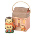 Hazel The Hedgehog resin ornament standing beside cottage house gift box on white background