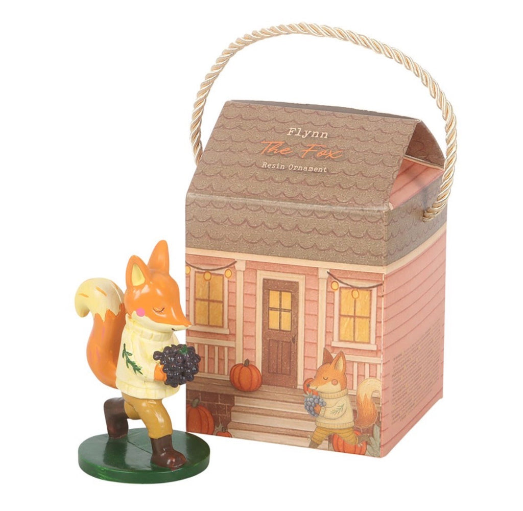 Flynn The Fox resin ornament standing beside cottage gift box on white background