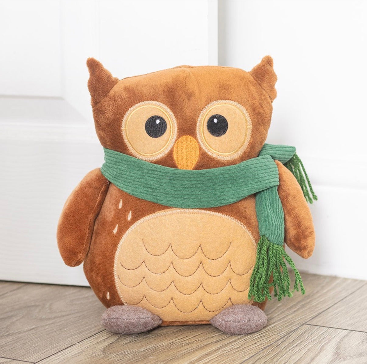 Oliver The Owl plush doorstop lifestyle shot propped against white door on wooden floor