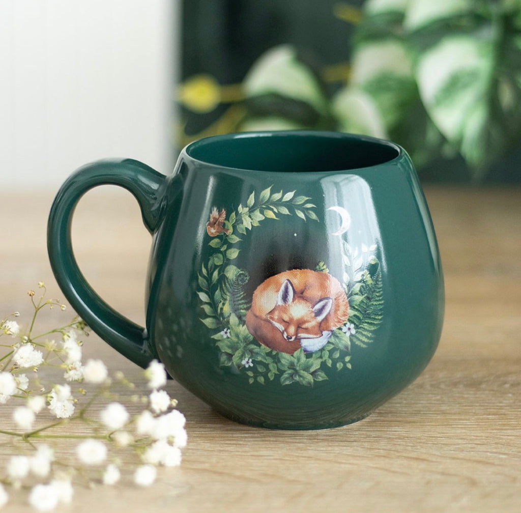 Enchanted Forest Sleeping Fox Mug in deep forest green styled with baby's breath flowers on a wooden surface