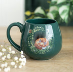 Enchanted Forest Sleeping Fox Mug in deep forest green styled with baby's breath flowers on a wooden surface