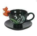 Dark green ceramic fox tea cup and saucer showing reverse side with botanical leaf and moon design, white background
