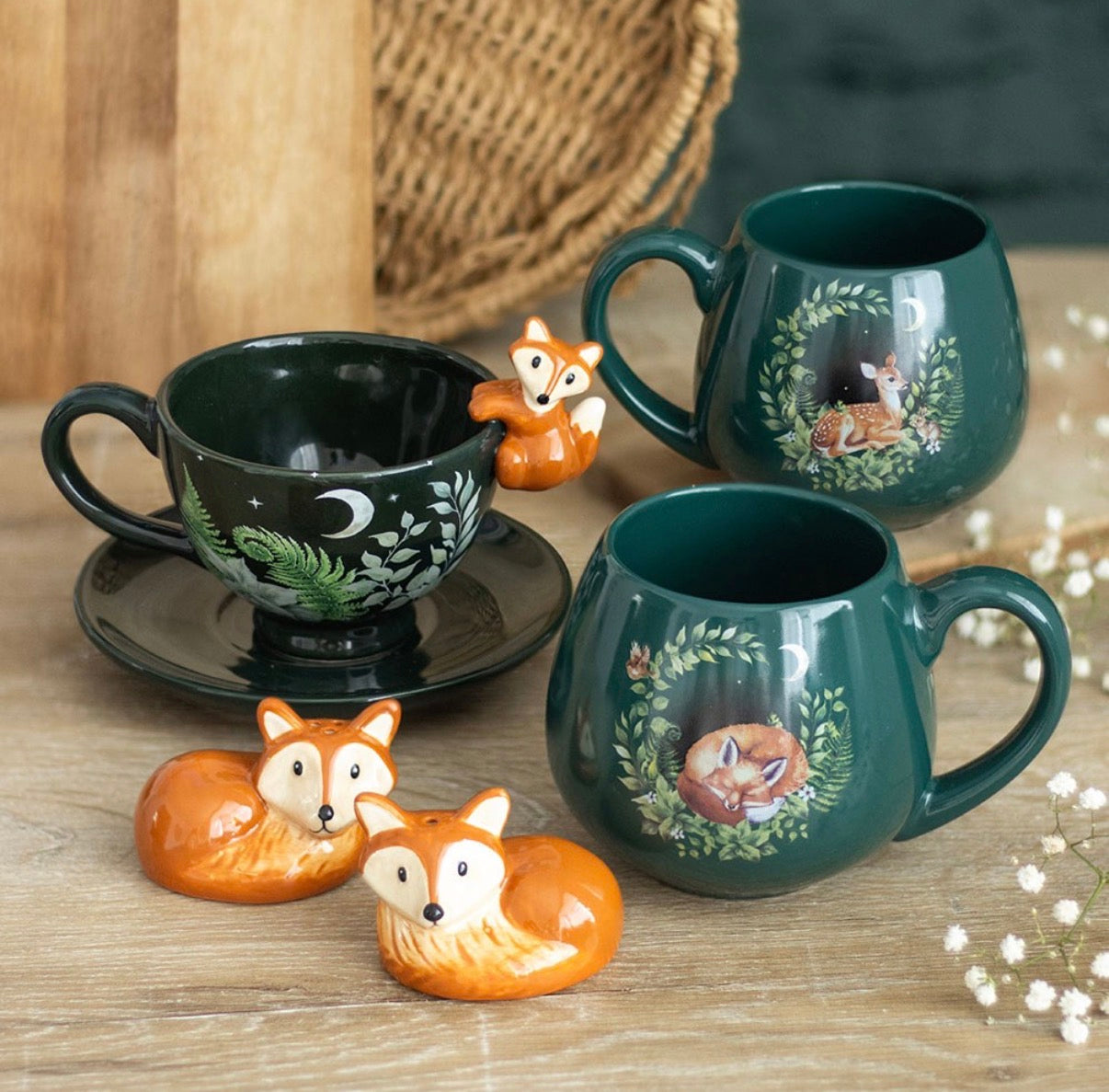 Enchanted forest fox tea cup alongside matching green ceramic mugs with woodland animal designs, styled flat lay