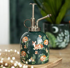 Dark green ceramic forest print plant mister with vintage silver pump, styled with gypsophila flowers and houseplants