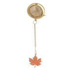 Gold mesh ball tea strainer with enamel maple leaf charm on chain, white background product shot