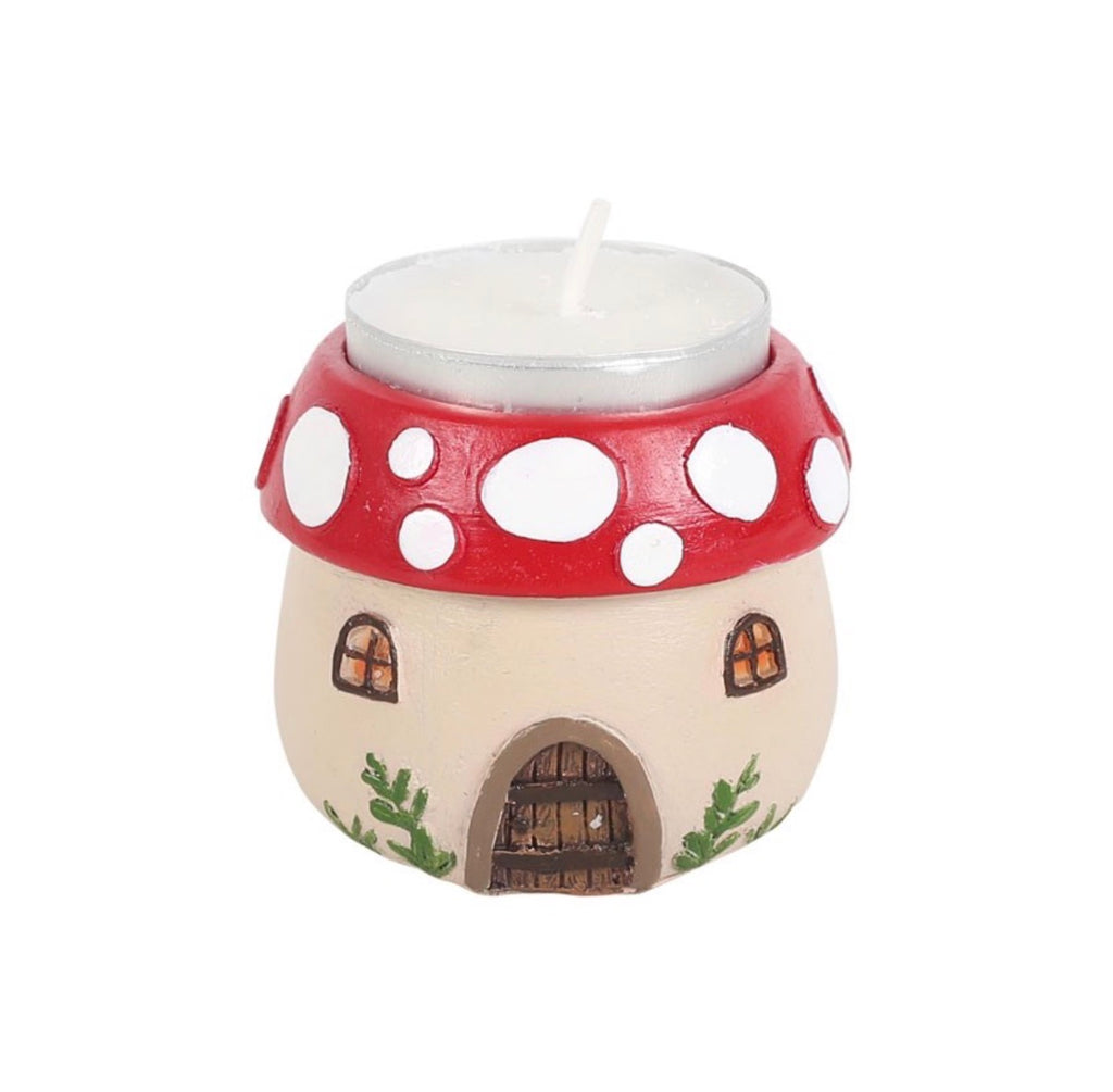 Mushroom house tealight holder with unlit tealight candle inserted, showing red spotted cap, arched door and lattice windows, white background