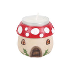 Mushroom house tealight holder with unlit tealight candle inserted, showing red spotted cap, arched door and lattice windows, white background