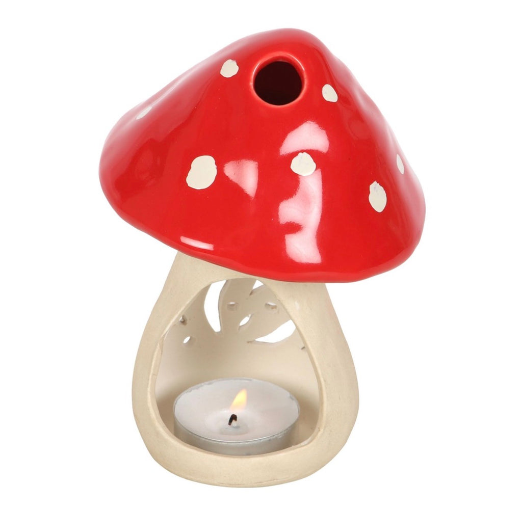 Small ceramic mushroom oil burner with cap lifted showing tealight candle underneath and oil bowl in red cap, white background