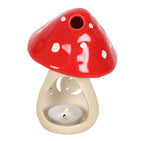 Small ceramic mushroom oil burner with cap lifted showing tealight candle underneath and oil bowl in red cap, white background