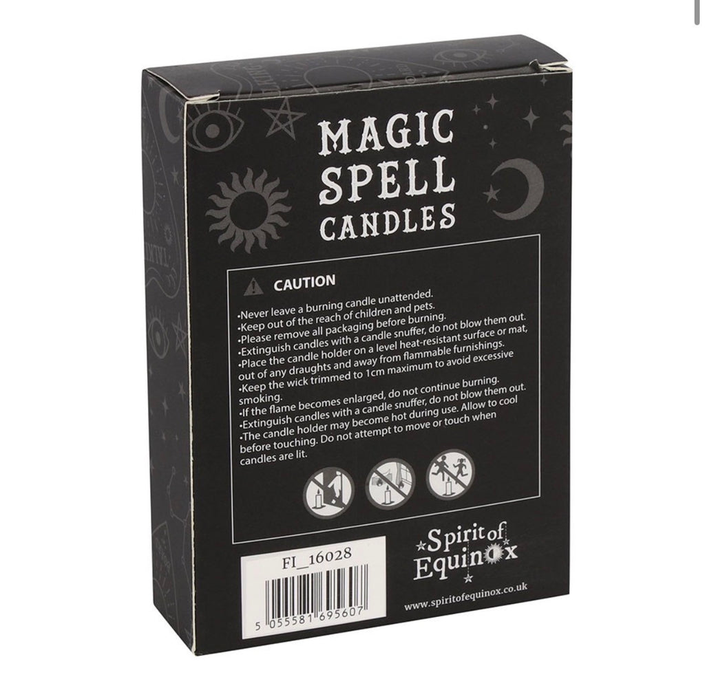 Hand holding a box of white Happiness spell candles beside lit candles and dried flowers