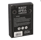 Hand holding a box of white Happiness spell candles beside lit candles and dried flowers