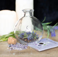 Empty glass spell jar with cork stopper beside the Protection Spell Jar recipe card