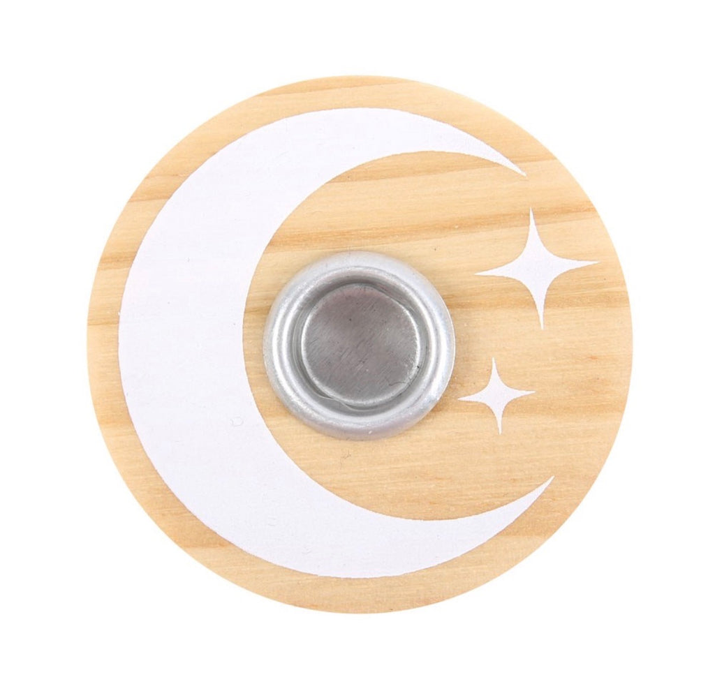 Lit white spell candle in the wooden moon and stars holder, styled with dried flowers