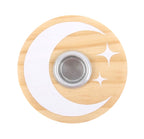 Lit white spell candle in the wooden moon and stars holder, styled with dried flowers