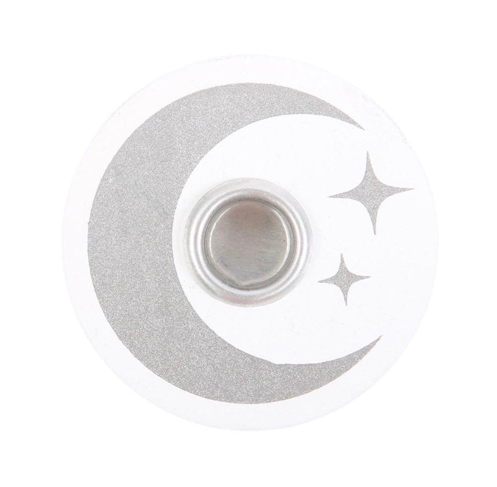 Lit white spell candle in the white and silver moon holder, styled with dried flowers