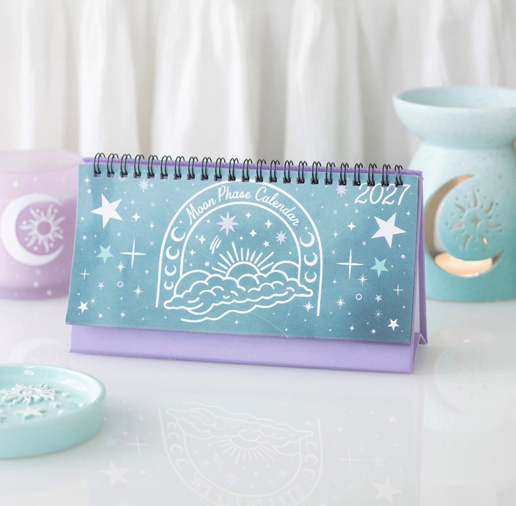 2027 Moon Phase Calendar standing on a desk beside a pastel wax burner