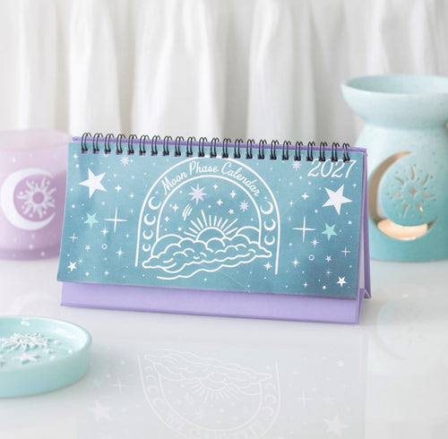 2027 Moon Phase Calendar standing on a desk beside a pastel wax burner
