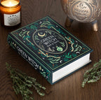 Green Witch Book of Spells box styled on a wooden table with a candle, cauldron and fresh herbs