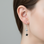 Crystal & Star Drop Earrings Sterling Silver worn shot — single silver hook earring with bezel-set clear CZ stone and polished star charm shown worn on model's ear against plain grey background"

